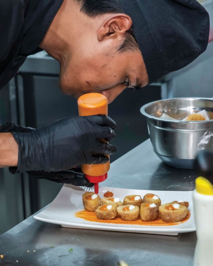 Chef finishing a plate of croquettes in the Tapas Outremer kitchen