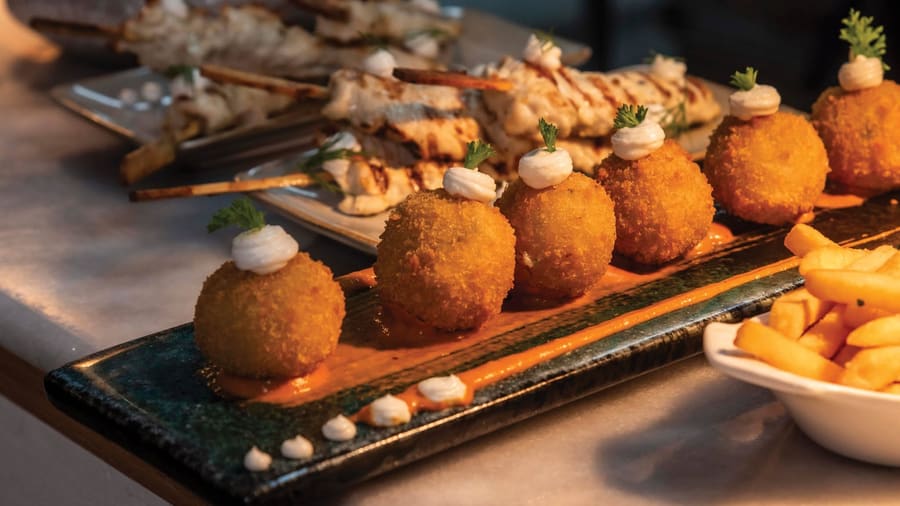 Croquettes and grilled skewers plated on the bar at Tapas Outremer